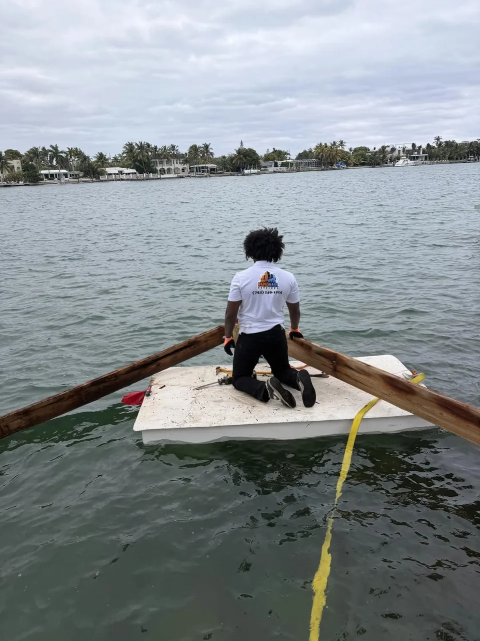 Crew member kneeling on a floating platform pulling dock boards