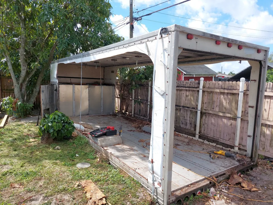Old box-truck body used as a backyard shed, side panels off