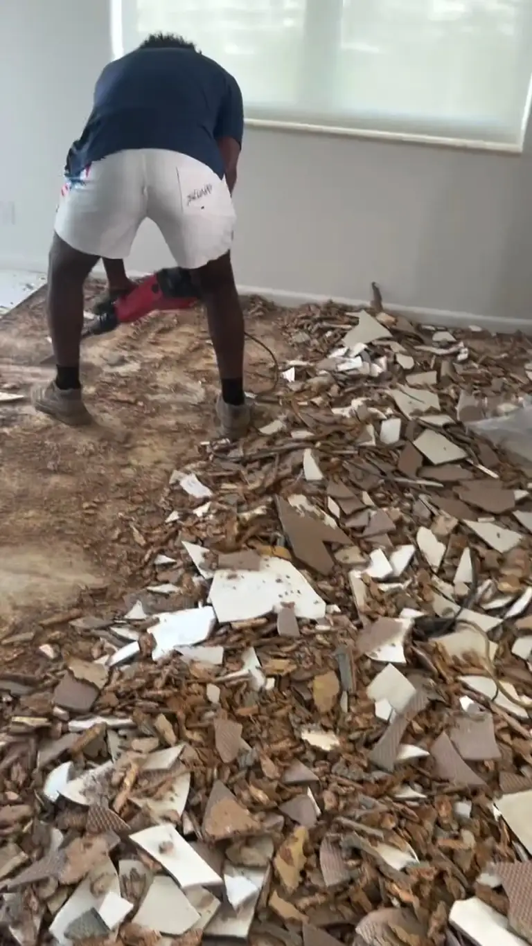 Crew breaking out floor tile inside a condo