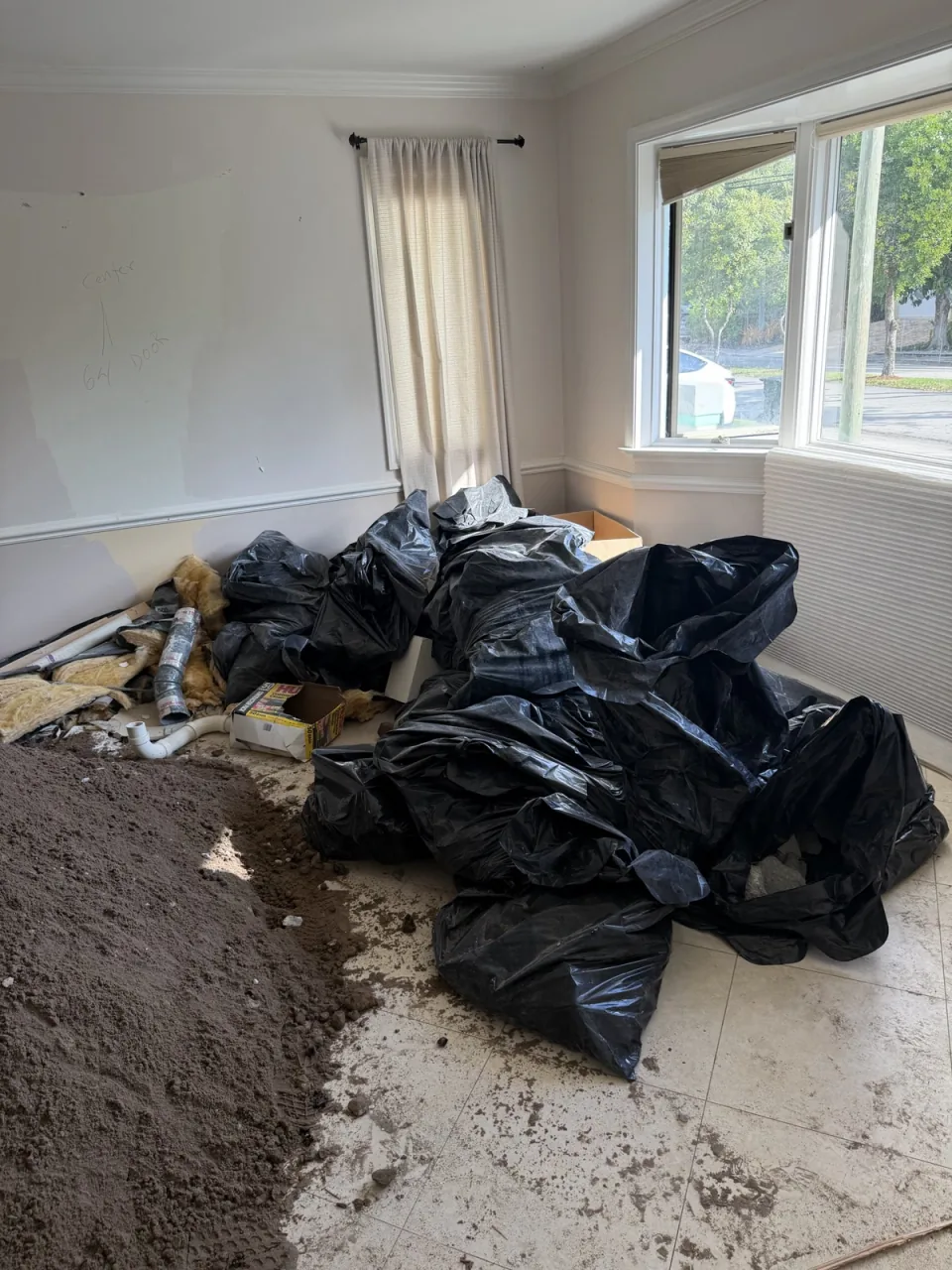 Room filled with black trash bags and debris before a Rapid Haul house cleanout