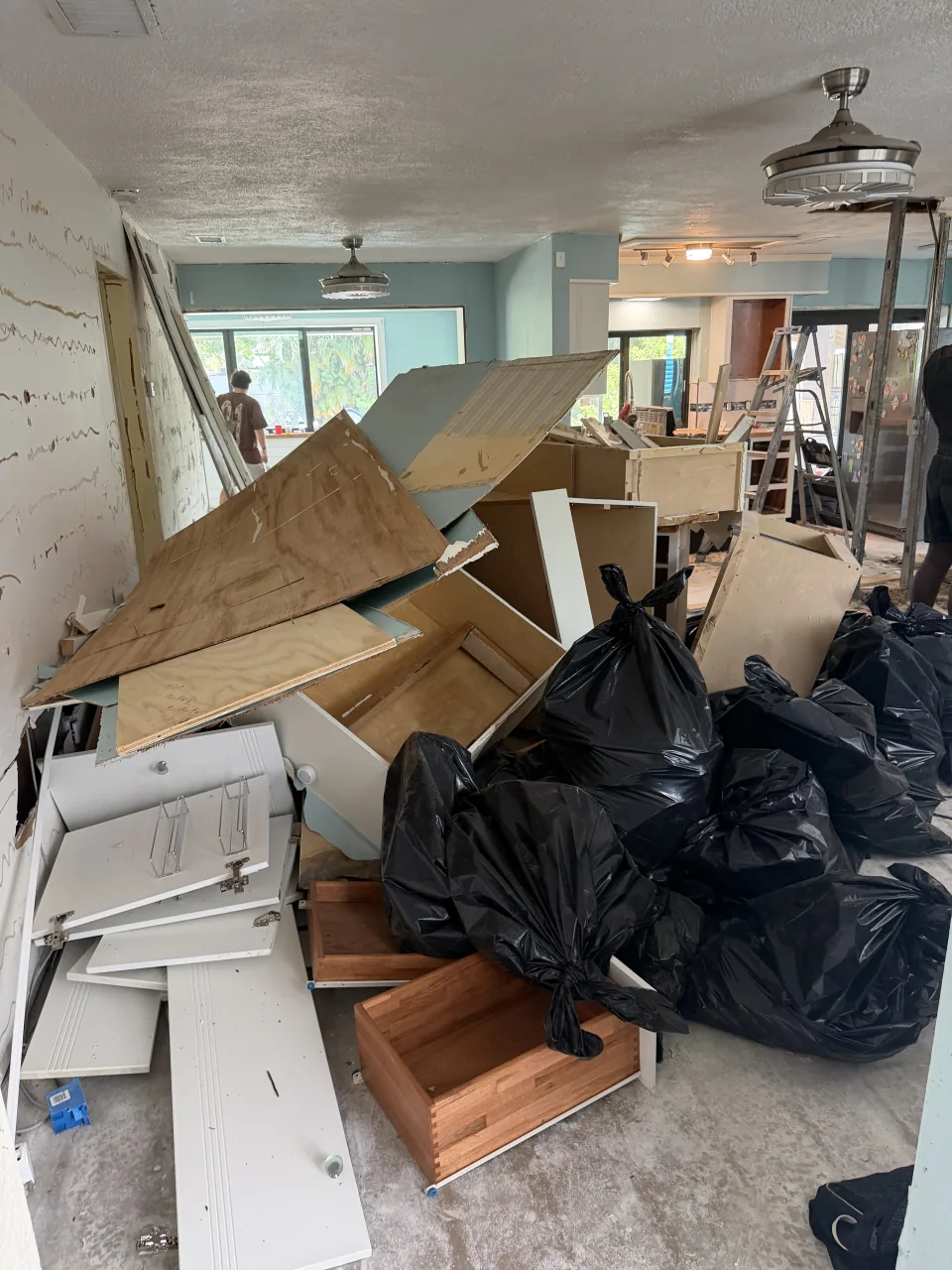 Torn-out kitchen cabinets, plywood and black debris bags piled in the middle of the Sunrise house during the interior demolition